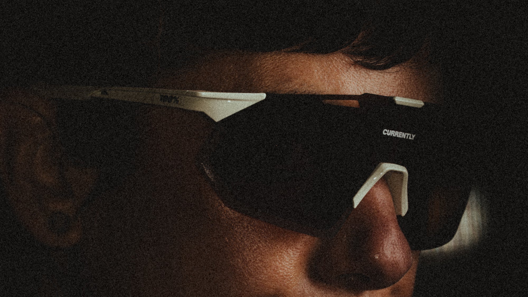 Currently Running™ x 100Percent® Collection - Featuring a girl runner wearing a Currently Running top and 100Percent Hypercraft® SQ Sunglasses on a dark-warm moody background.